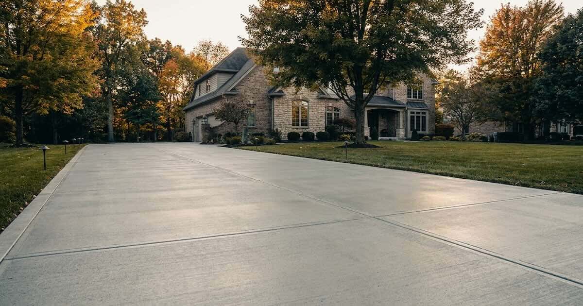 Sealed concrete driveway leading to an upscale brick-and-stone home in Carmel, Indiana