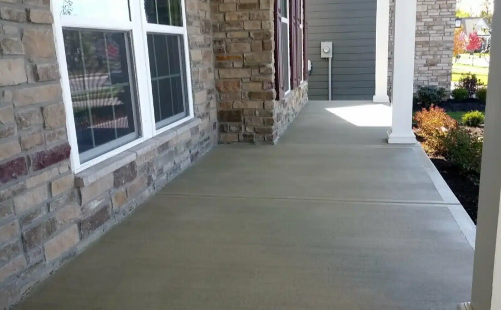 Natural-tone stained concrete front porch with stone column